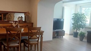 Un coin repas avec une table et des chaises en bois, un téléviseur et des plantes en pot.