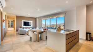 Eine moderne Küche mit einer großen Kochinsel, einem Essbereich mit einer Couch und Blick auf die Stadt.
