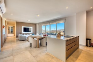 Une cuisine moderne dotée d’un grand îlot central, d’un coin repas avec un canapé et d’une vue sur la ville.