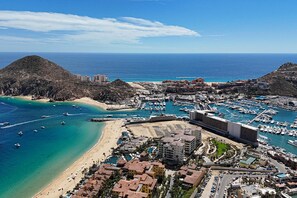 Eine Küstenstadt mit einer Marina, Strand und einem Bergpanorama.