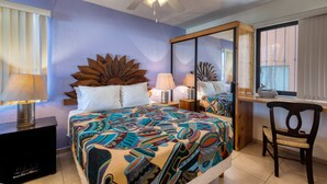 Quarto com cama, escrivaninha, cadeira, ventoinha no teto e um espelho grande.