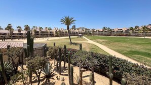 Hotel com jardim no deserto, palmeiras e céu azul límpido.