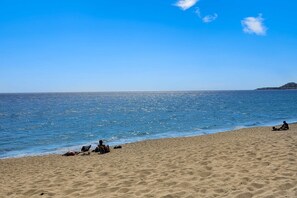 A beach with sand and water, a distant island, and a clear sky. - Inviting apartment across from the beach with pool, grill, balcony & golf nearby (San José del Cabo)