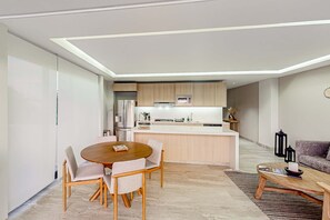 A modern kitchen with a central island, a dining area with a round table, and a living space with a sofa and coffee table. - Downtown condo with great views, shared pool, hot tub, & grill (San José del Cabo)
