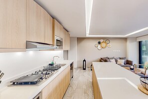 A modern kitchen with wooden cabinets, a gas stove, and a microwave. - Downtown condo with great views, shared pool, hot tub, & grill (San José del Cabo)