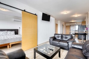 A modern living space with a bed, sofa, coffee table, and a kitchen area. - Ocean view condo with scenic balcony, well-equipped kitchen, internet, & W/D (Cabo San Lucas)