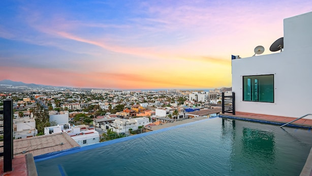 Ein Pool auf dem Dach mit Blick auf die Stadt, ein weißes Gebäude mit Satellitenschüsseln und ein klarer Himmel.