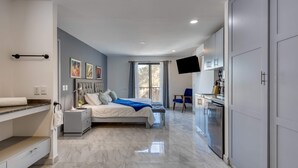 Camera da letto moderna con un letto, comodini, una scrivania, una TV a schermo piatto e un armadio.