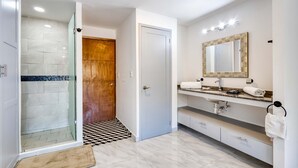 Un bagno moderno con doccia, mobile lavabo e un ampio specchio.
