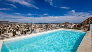 Una piscina sul tetto con vista sulla città, che include una montagna e degli edifici.