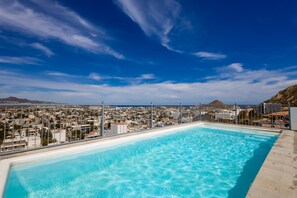 A rooftop pool with a cityscape view, including a mountain and buildings. - Hotel room with ocean-view rooftop infinity pool, AC, & gym - dog-friendly (Cabo San Lucas)