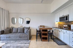 Una cocina moderna con armarios blancos, un microondas y un comedor con mesa y sillas.