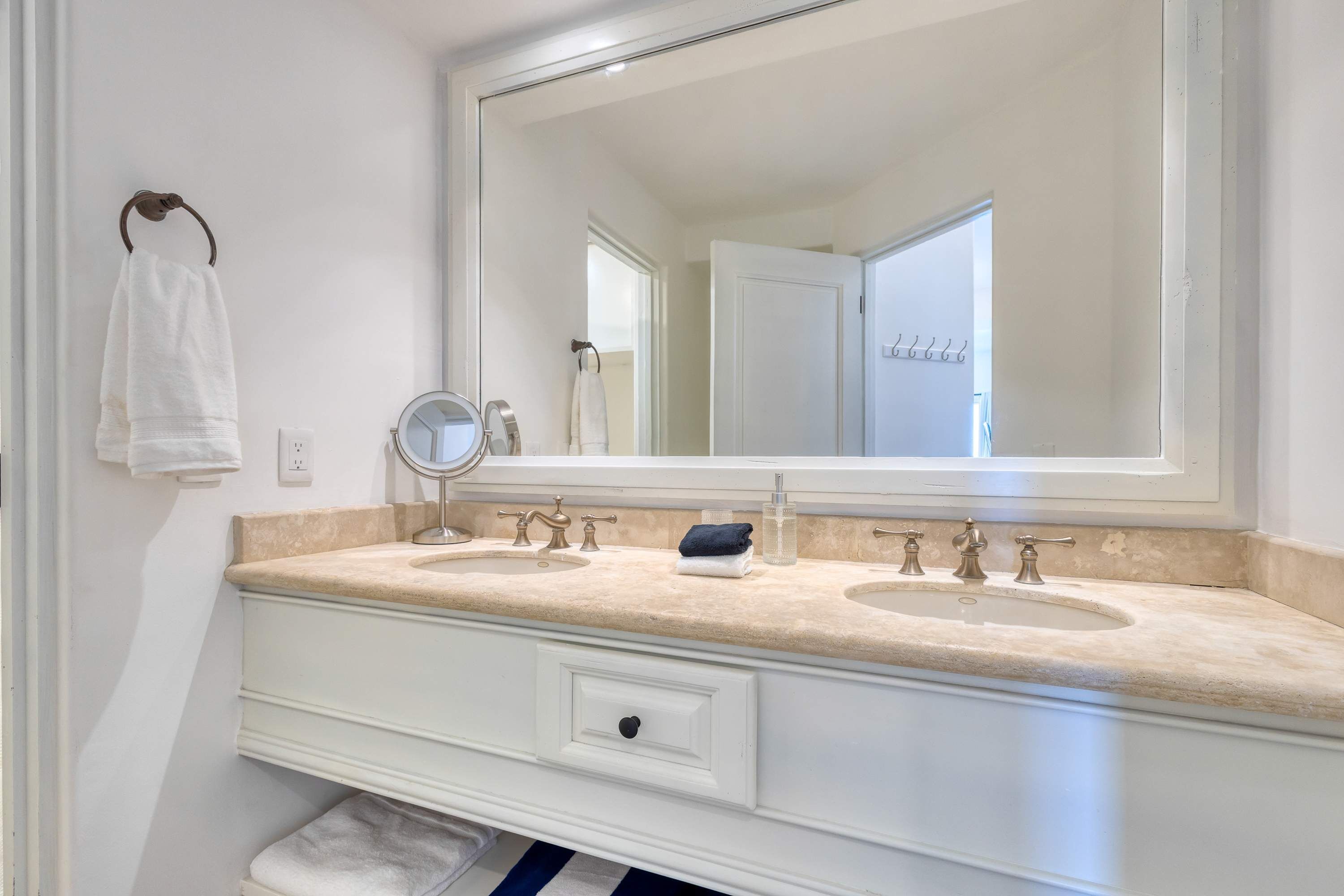 Une salle de bain avec un meuble-lavabo à deux vasques, un grand miroir et un porte-serviettes.