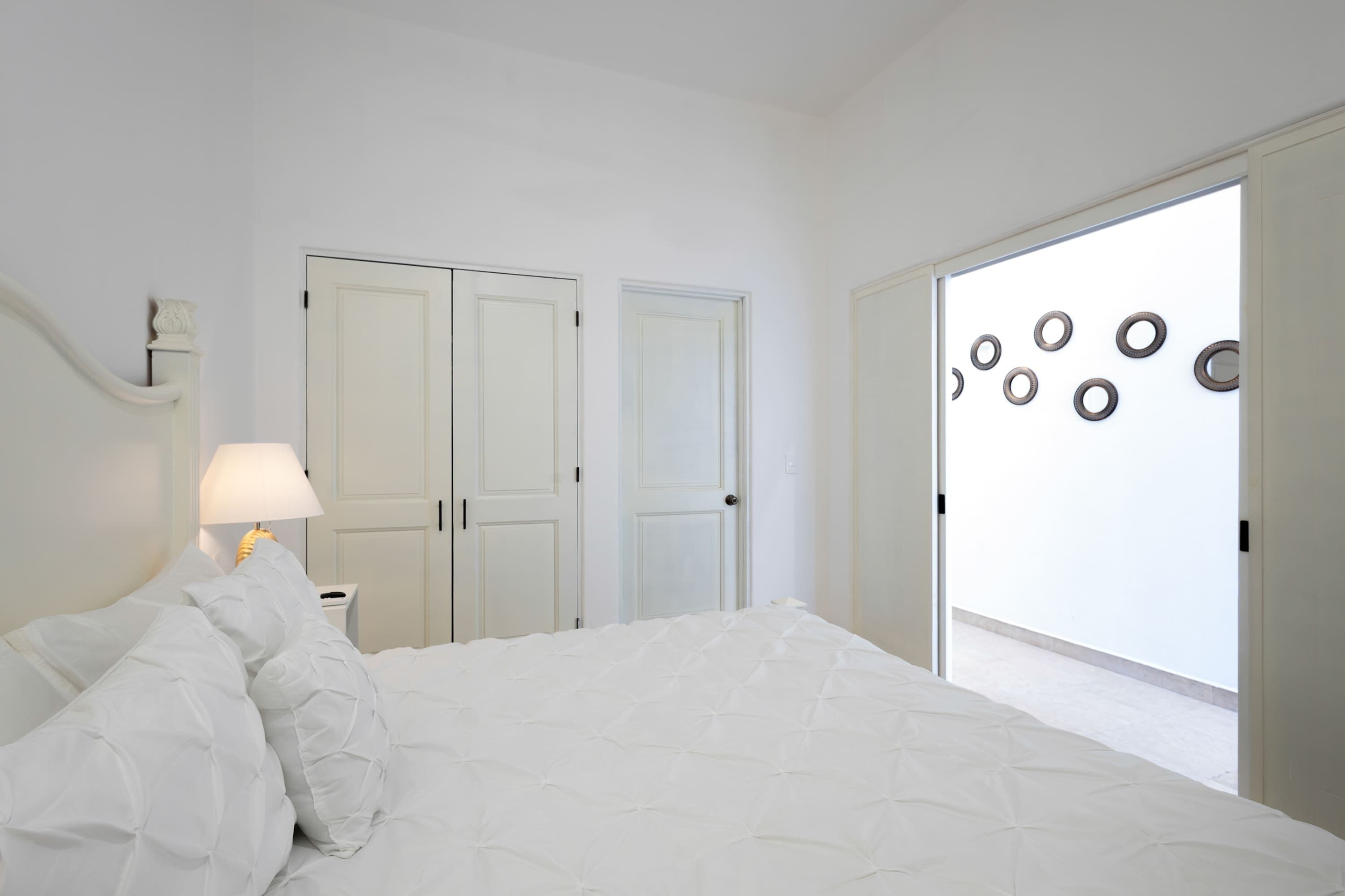 A bedroom with a bed, a nightstand, a lamp, and a door with circular decorations.