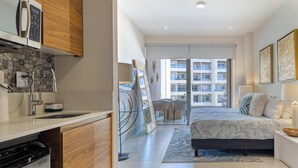 Una habitación de hotel moderna con cocina, una cama grande y vistas a la ciudad.