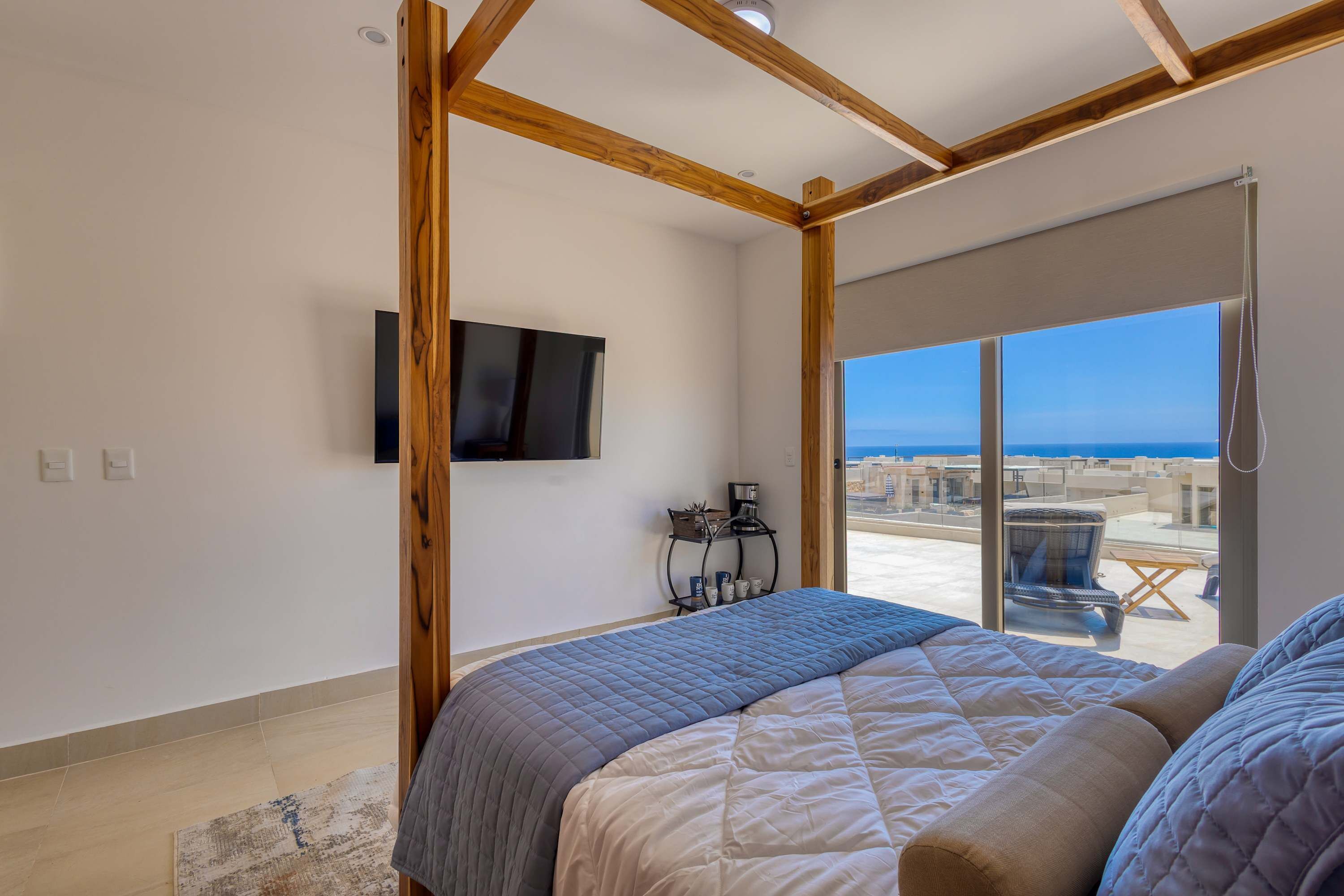 Ein Schlafzimmer mit Bett, Fernseher, Fenster mit Aussicht und Balkon.