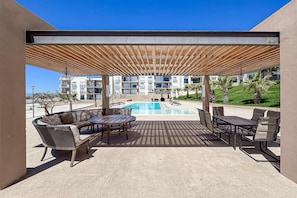 Eine Außenpatio mit Pool, Sitzgelegenheiten und Blick auf ein Gebäude im Hintergrund.