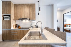 Eine moderne Küche mit Holzschränken, einem eingebauten Ofen, einer Spüle aus Edelstahl und einer Arbeitsplatte aus Granit.