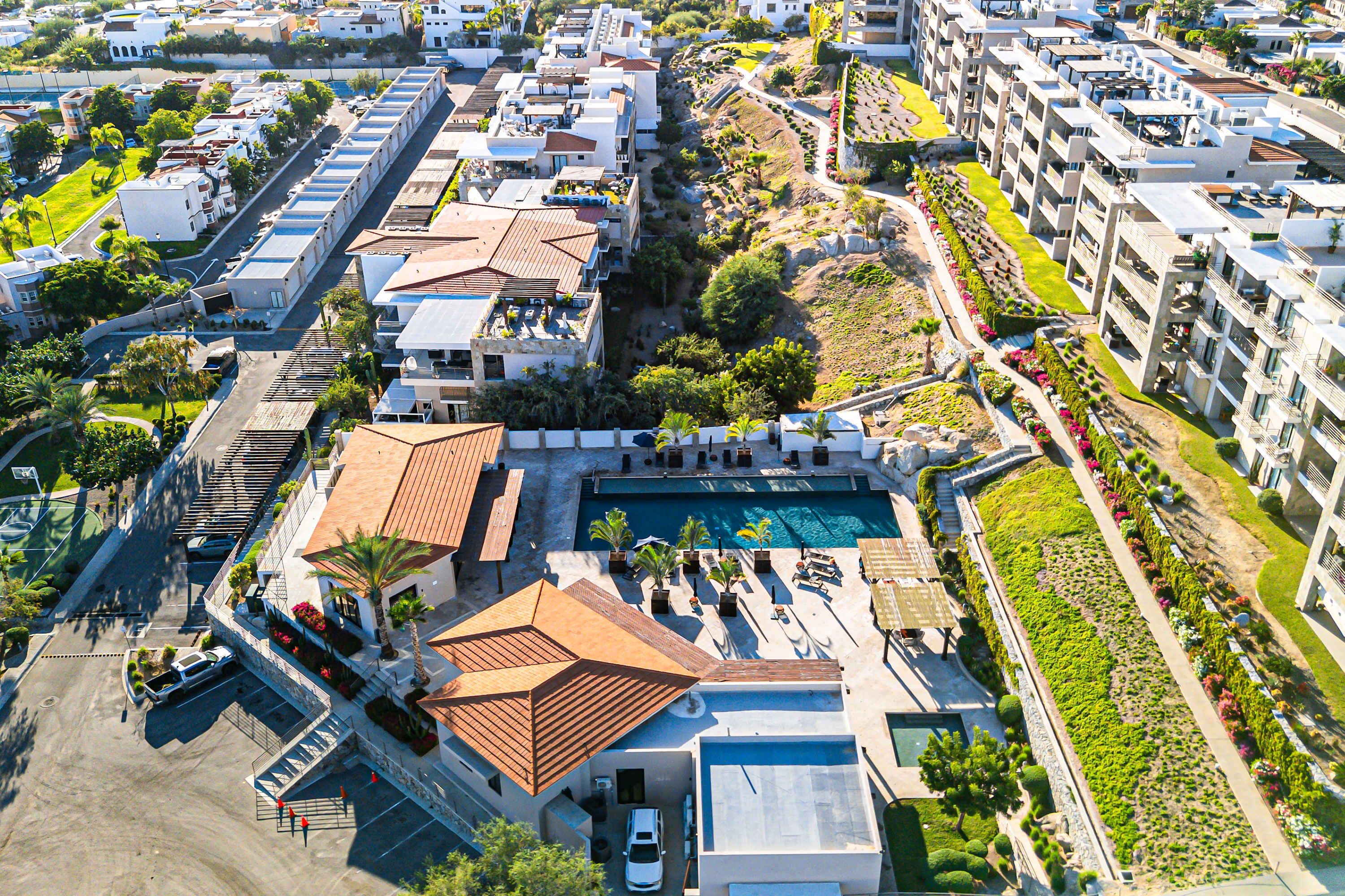 An aerial view of a hotel with multiple buildings, a swimming pool, and landscaped areas.