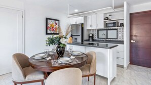 A modern kitchen with white cabinets, a black countertop, and a dining area with a round table and four chairs. - Morgan Residences 508A @ Boutique Hotel with pool, gym, spa (Cabo San Lucas)
