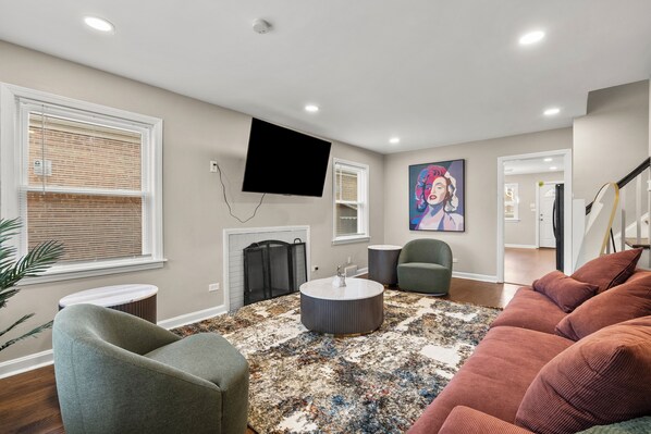 A living room with a fireplace, a flat-screen TV, and a large painting on the wall.