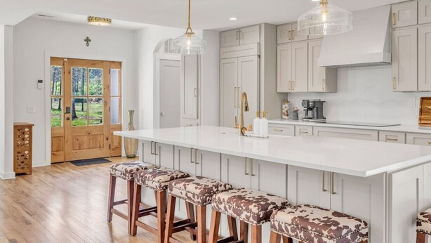 Una cucina moderna con un'isola grande, sgabelli da bar e illuminazione a sospensione.