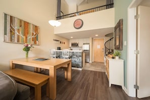 A spacious living area with a dining table, kitchen, and a staircase leading to an upper level. - 1 BR + Loft - Spacious and Great for Families (Whistler)