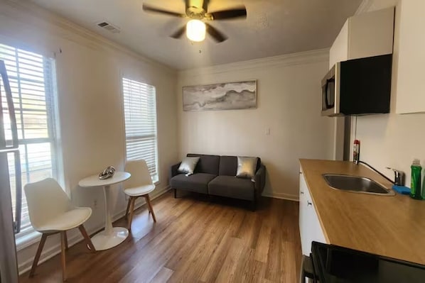 Une cuisine compacte avec un coin repas, un ventilateur de plafond, un four à micro-ondes et un tableau accroché au mur.