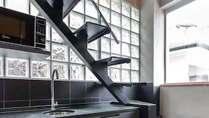 A modern kitchen with a black staircase, a microwave, and a sink. - ZEST Pedroso (São Paulo)