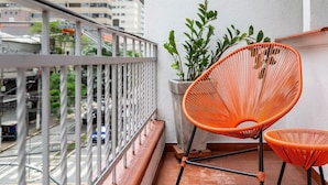 A balcony with a white railing, two orange chairs, and a potted plant. - ZEST Pedroso (São Paulo)