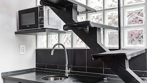 A kitchen with a black countertop, a sink, a dishwasher, and a microwave. - ZEST Pedroso (São Paulo)