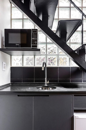 A kitchen with a microwave, sink, and a window with a view.