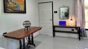 A room with a wooden desk, a chair, a painting, a door, a mirror, a laptop, and a lamp. - Serene Cabin Retreat in Cuajiniquil, Costa Rica (La Cruz)