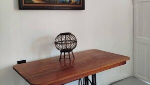 A room with a wooden table, a chair, a framed painting of a lighthouse, and a white door. - Serene Cabin Retreat in Cuajiniquil, Costa Rica (La Cruz)