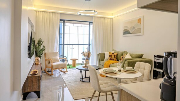 Uma sala de estar moderna com sofá, mesa de jantar e máquina de café.