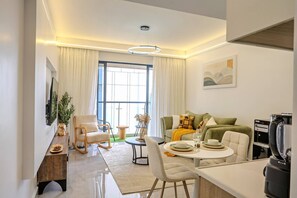 A modern living room with a sofa, dining table, and a coffee machine.