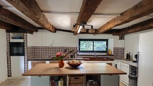 Una cocina con una isla central, vigas de madera, una ventana y salpicadero de azulejos.