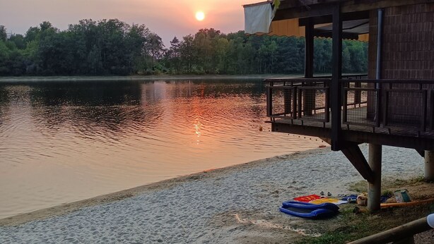 Vista al lago con una estructura de madera, un muelle y un atardecer.