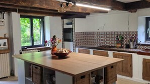 Una cocina con una isla grande, vigas de madera, salpicadero de azulejos y un ventanal con vistas.