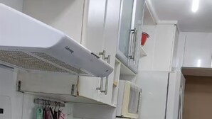Una cocina con armarios blancos, una campana extractora y un electrodoméstico rojo.