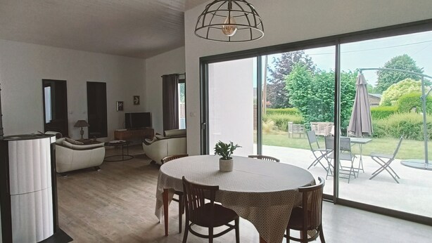 A modern interior with a dining area, a kitchen, and a large sliding glass door leading to an outdoor patio. - 3-bedroom house, located 2mns from the Nantes-Brest canal and its walks! (Plessé)