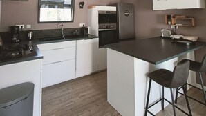 A modern kitchen with a central island, a built-in oven, and a refrigerator. - 3-bedroom house, located 2mns from the Nantes-Brest canal and its walks! (Plessé)