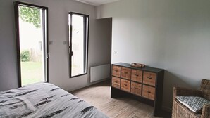 A bedroom with a bed, a dresser, a chair, and a large window. - 3-bedroom house, located 2mns from the Nantes-Brest canal and its walks! (Plessé)