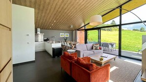 Un interior moderno con cocina, comedor y sala de estar con ventanas amplias.