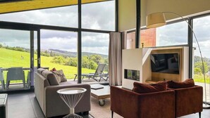 A modern living room with a sofa, a coffee table, and a TV. - Luxury ski-in ski-out villa Winterberg | sauna | corner location | views (Winterberg)