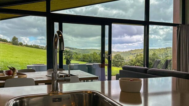Una cocina moderna con un ventanal grande, un lavamanos y un comedor con vistas a un paisaje verde.