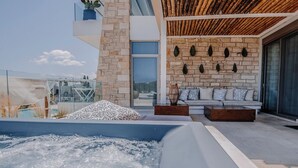 Ein moderner Außenbereich mit Whirlpool, einer Steinwand, einer Holzbeschichtung und einer Sitzecke mit Kissen.