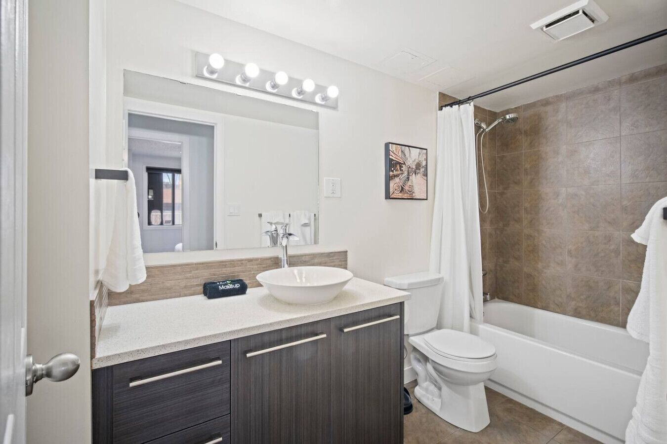 A bathroom with a vanity, sink, mirror, and shower.