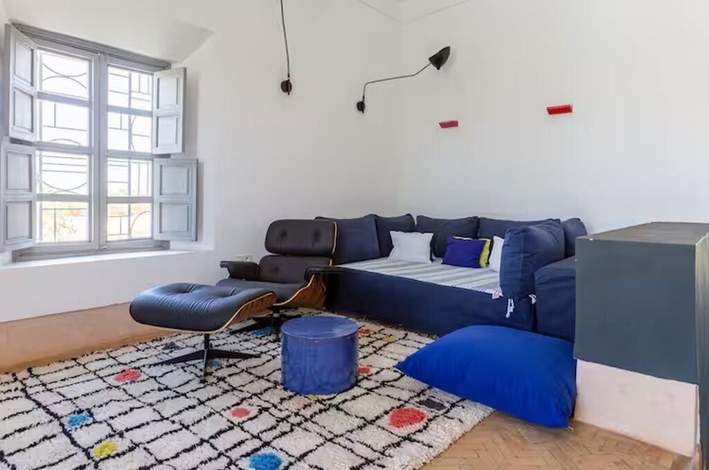 Una sala moderna con sofá, reposapiés y un tapiz estampado.