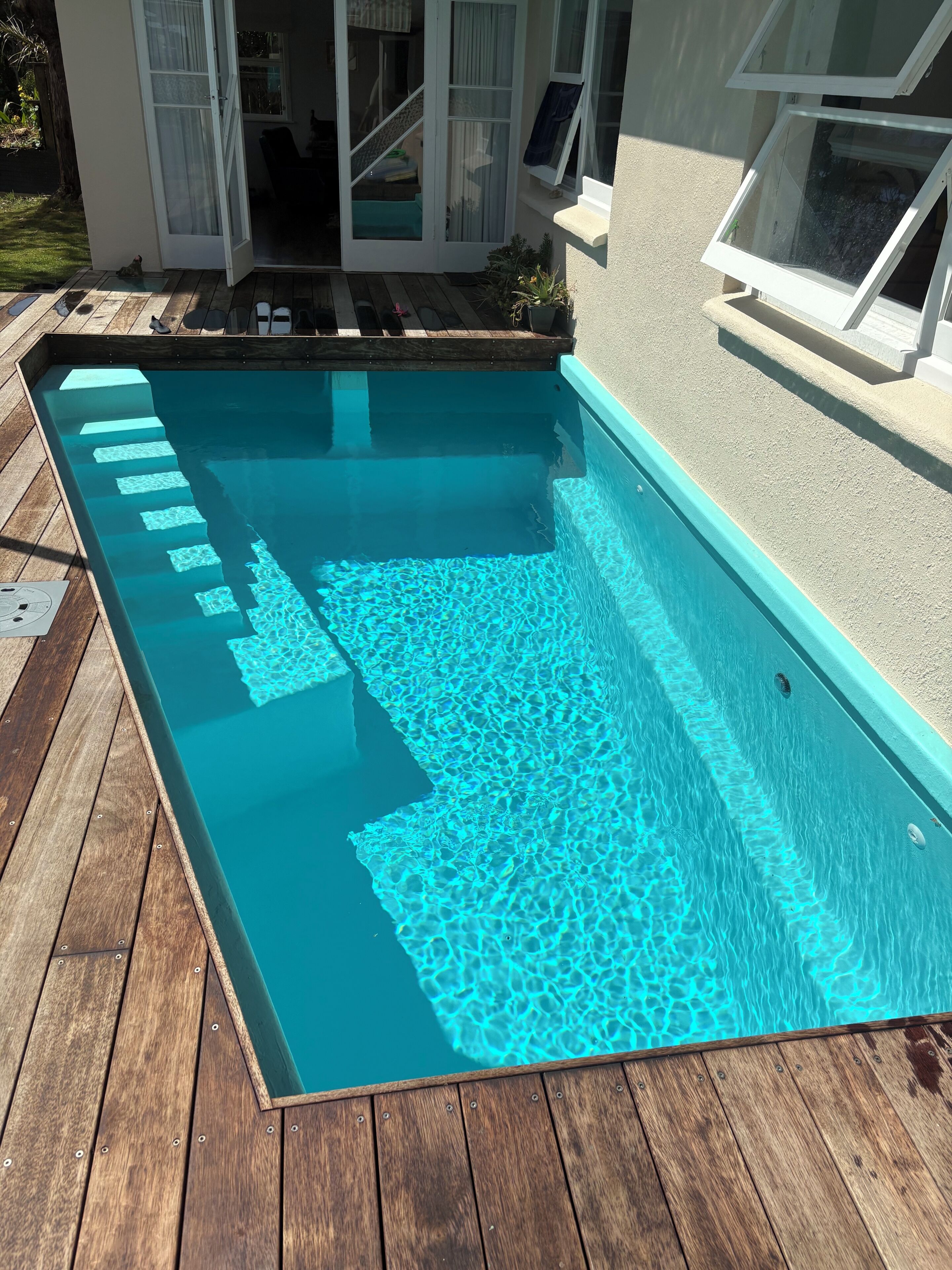 A rectangular swimming pool with a wooden deck surrounding it.